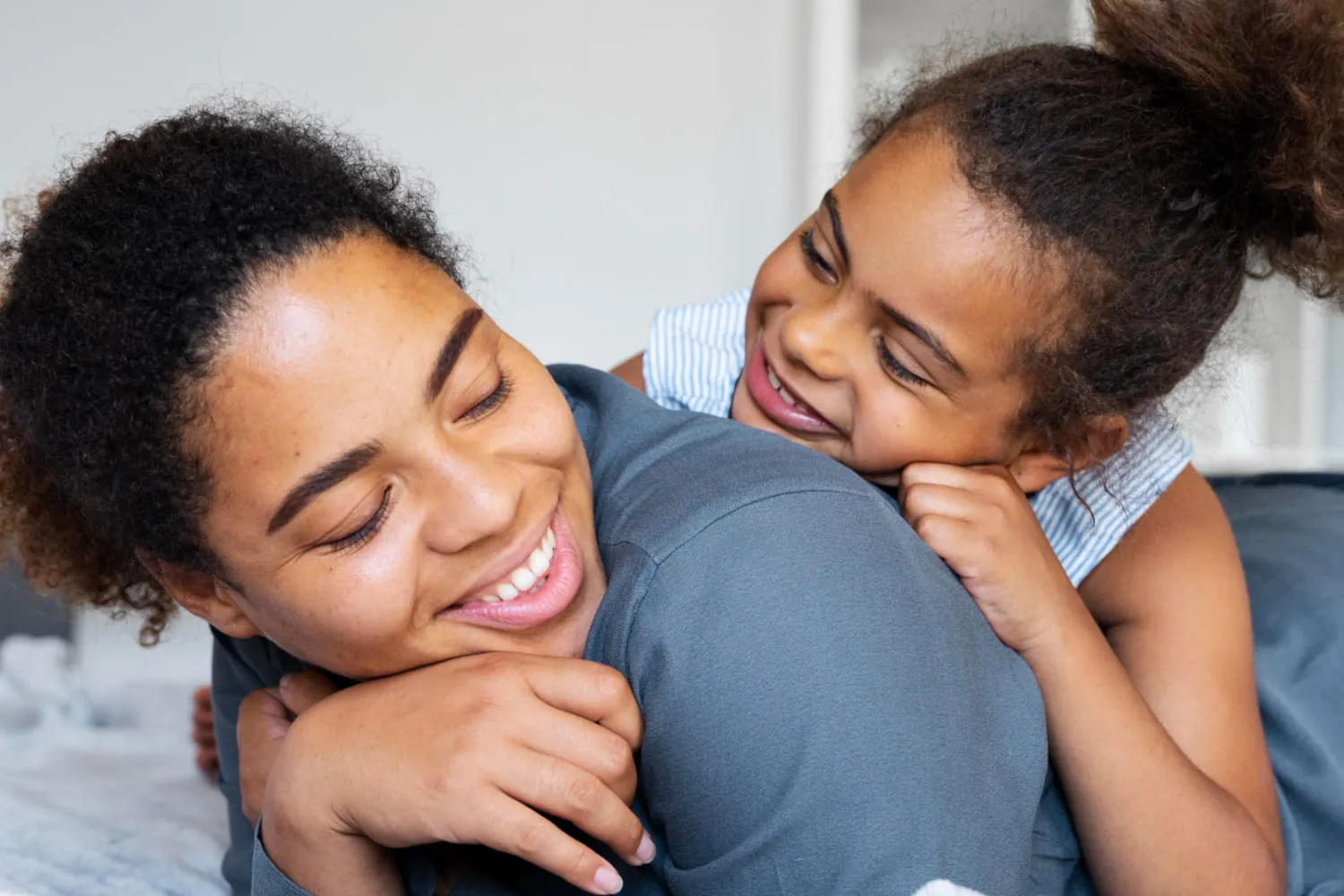 A mother and her daughter sharing a long, happy hug at home
