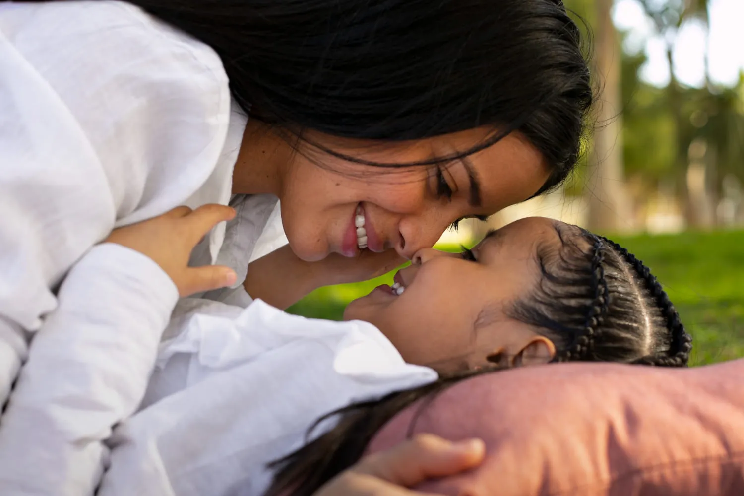 A mother and her daughter lying face to face on the grass, smiling