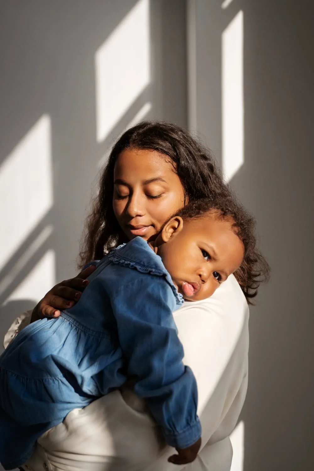 A smiling mother holding her young son, both dressed in denim